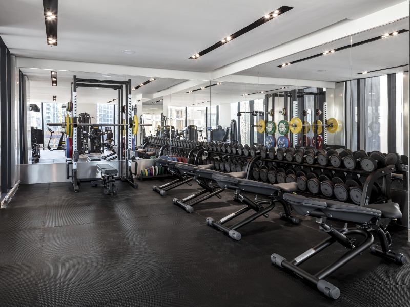 Interior photo of residents gym, with weight equipment, benches and racks of free weights and dumbbells