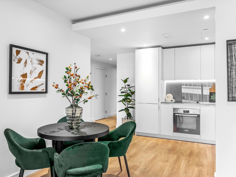 Interior photo of the dining area table and green chairs and kitchen, One bedroom Showhome