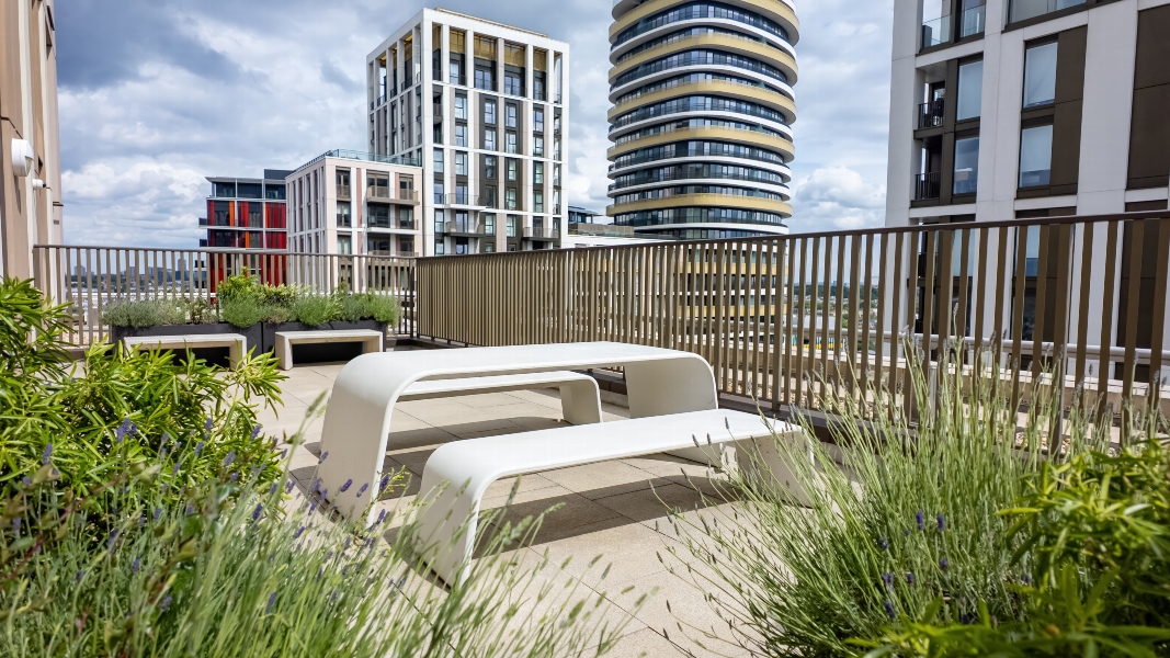 Exterior view from the terrace at the White City Apartments 15th Floor, with white table and benches with building views in the background