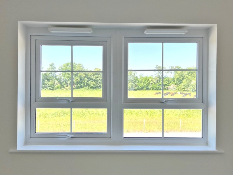 View through a window in a bedroom at Rogerson Gardens, overlooking a field with cows and trees
