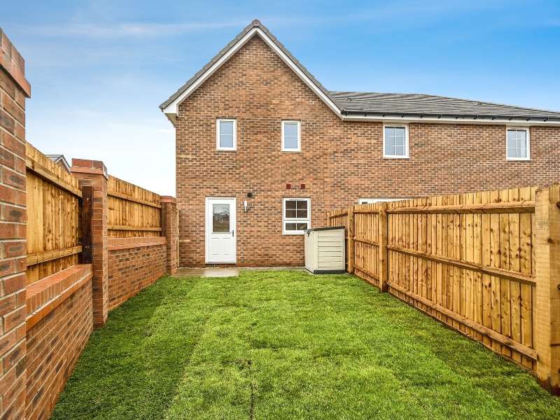 Photo of the garden exterior looking towards the rear of the house of a three bedroom house at Meden Meadow, showing the garden storage, lawn and fencing