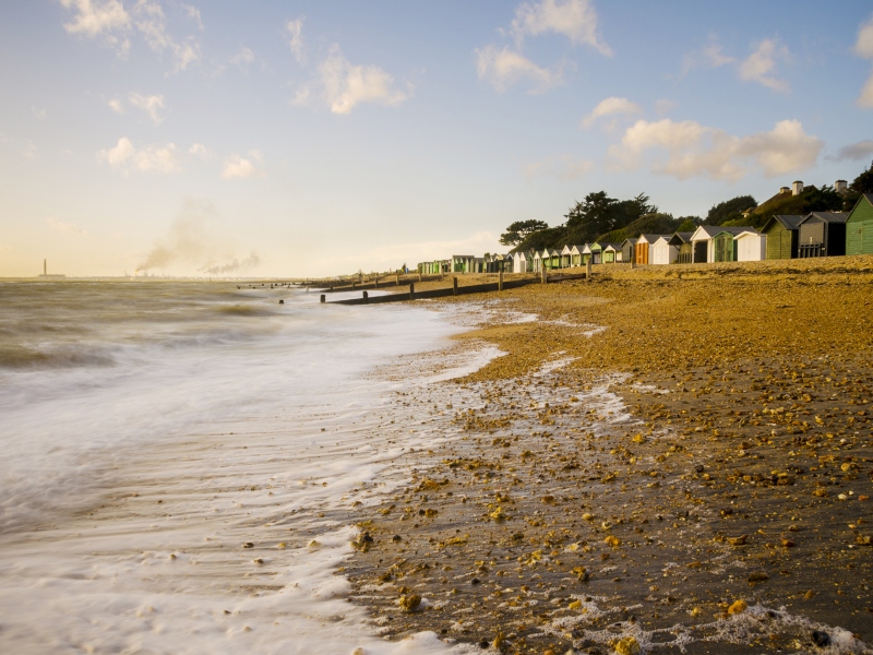 Photo taken of Hill Head Beach - looking down the shoreline and sea, with beach huts in the background