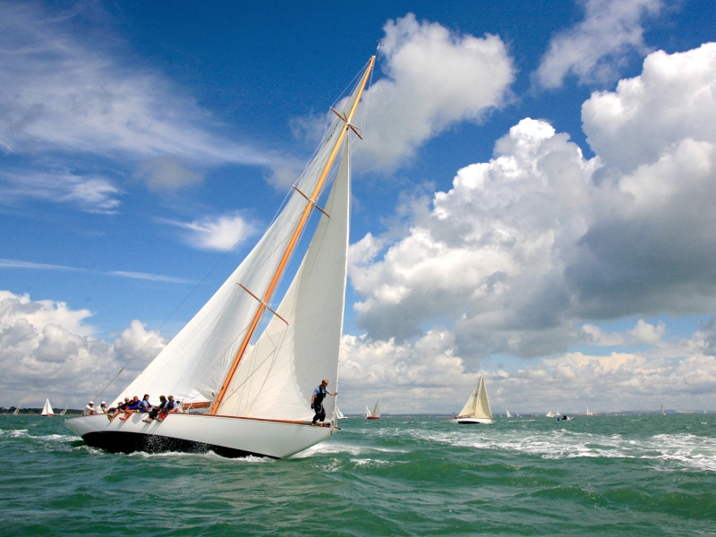 Photo of a sailboat with sails up racing on the Solent