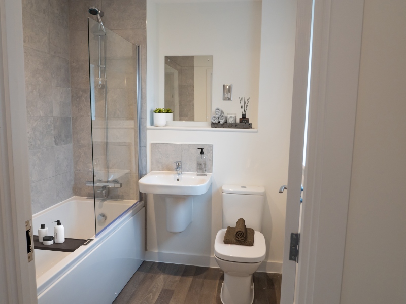 Interior view of a CGI dressed bathroom taken in an actual 3 bed house at Benson Grange, showing bath with glass screen, handbasin and toilet.