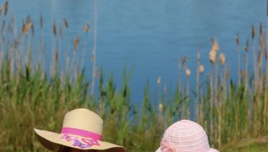 Two children wearing hats, sitting on a bench in front of Stanwick lake