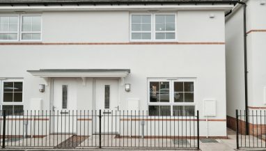 Exterior photo of an actual three bedroom Shared Ownership house at Lower, Lane, Coleford,. Exterior rendered in white, with railings in front of car parking space