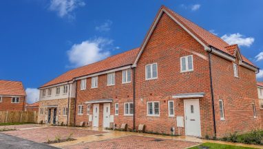 Exterior view of a terrace of homes at Sorrel Grove, Norfolk, with parking spaces and lawn outside