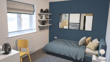 Interior view of a CGI dressed double bedroom taken in an actual 4 bedroom house at Benson Grange, showing a single bed, desk and chair, shelves and framed art